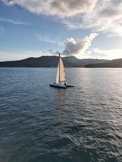 A sailboat on calm water with a mountainous backdrop. 1