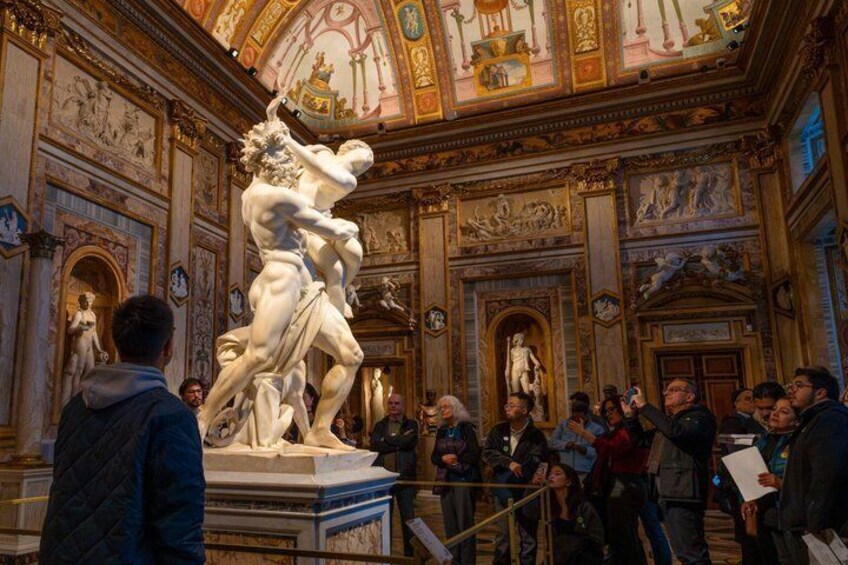 A marble sculpture in a grand hall with ornate ceiling and wall decorations. 3