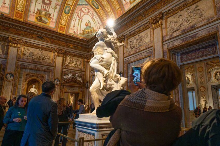 A marble statue in a museum with ornate ceiling and walls. 2