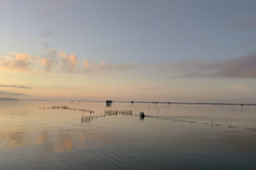 A calm water body with a distant structure and sparse vegetation. 3