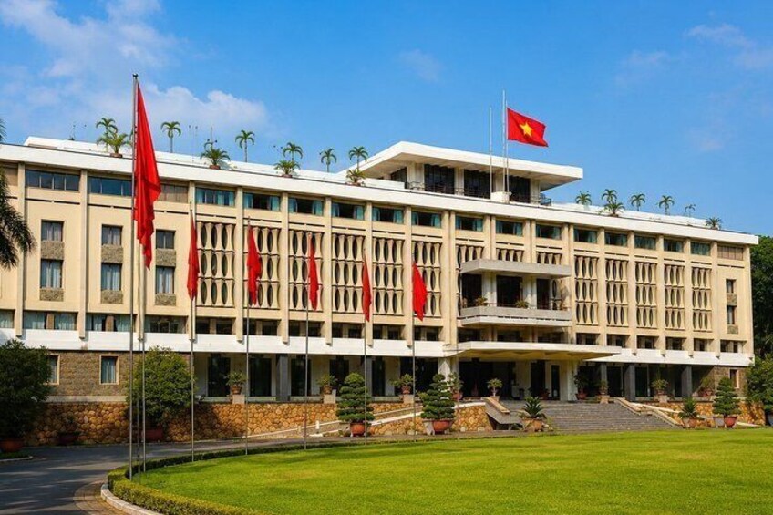 A large building with multiple red flags, a clear blue sky, and a well-maintained lawn. 5