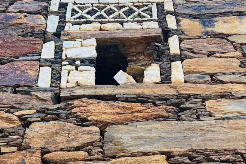 A stone structure with a central opening, surrounded by a patterned stone border. 3