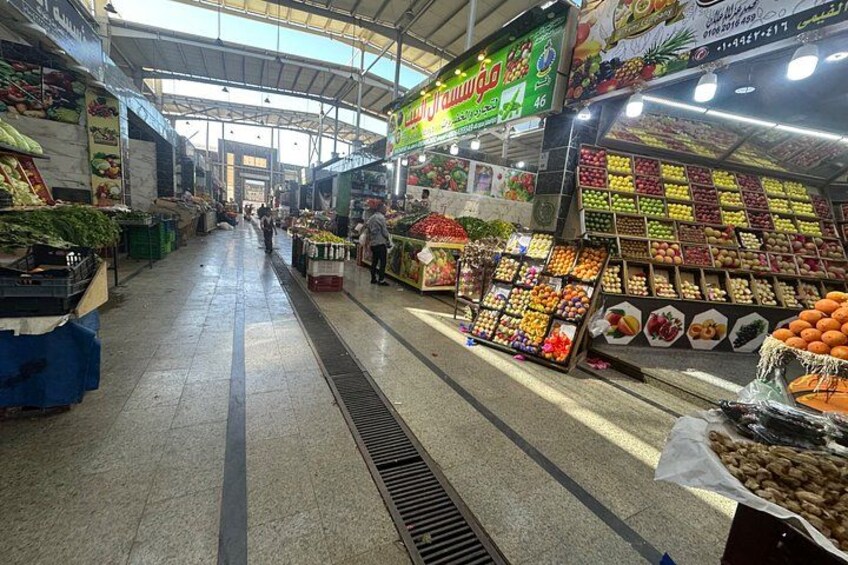 A market aisle with produce stands, a ventilation system, and a ceiling structure. 4