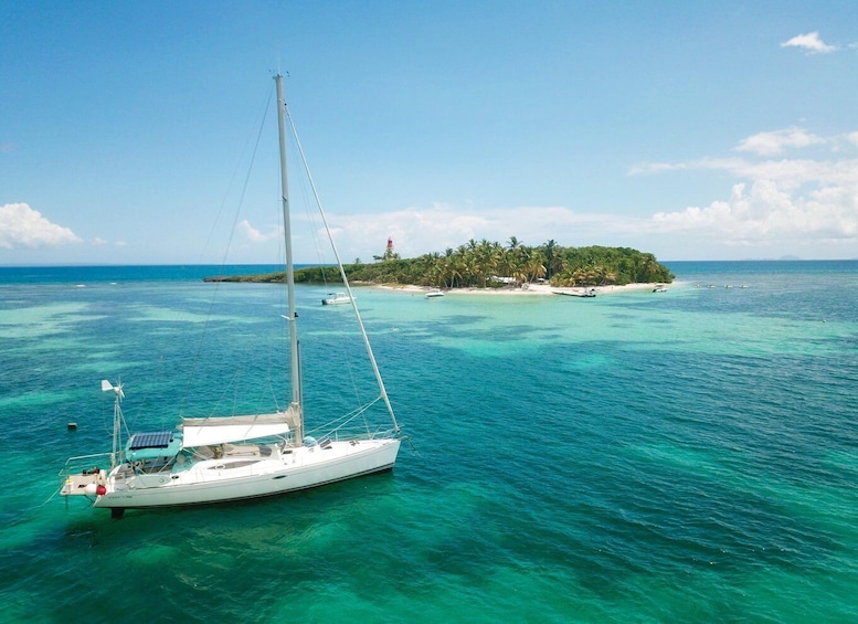 A sailboat on turquoise waters with a tropical island in the background. 5