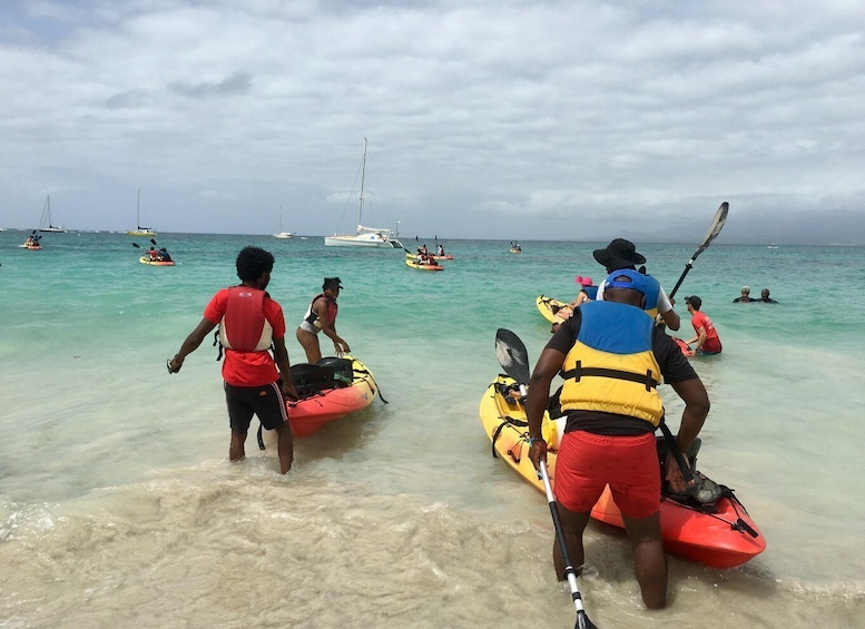 People preparing kayaks on a beach with boats in the background. 4
