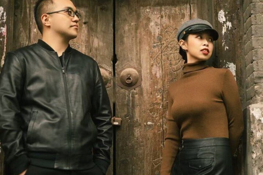 Two people standing in front of a rustic wooden door. 1
