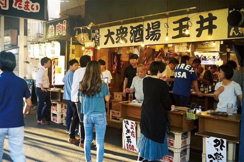 A bustling street food market with people queuing at food stalls. 4