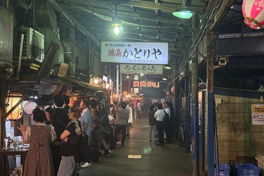 A crowded indoor market with people browsing and shopping. 2