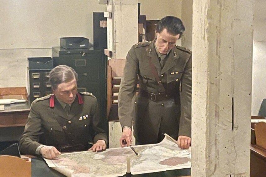 Two individuals in military uniforms examining a map. 5