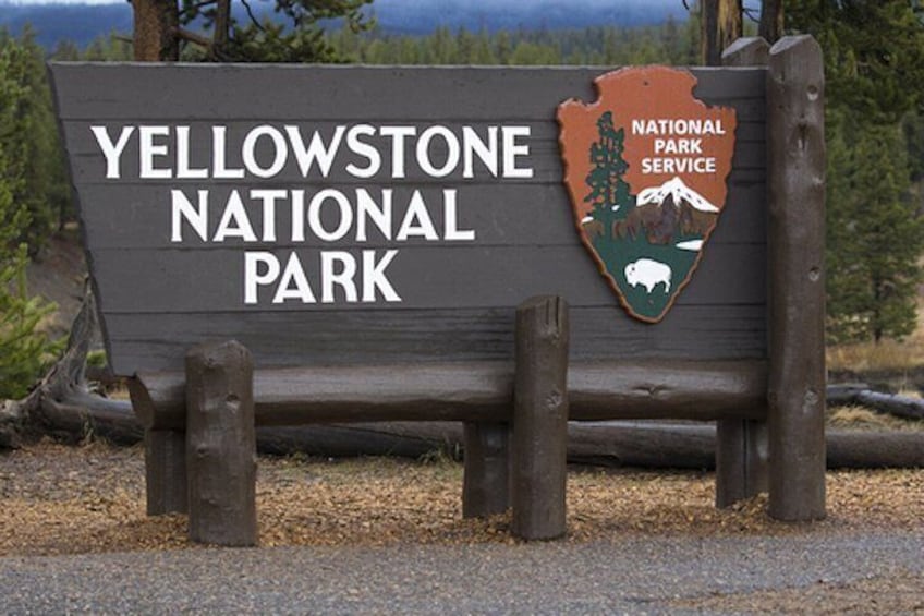A wooden sign for Yellowstone National Park with a logo. 4