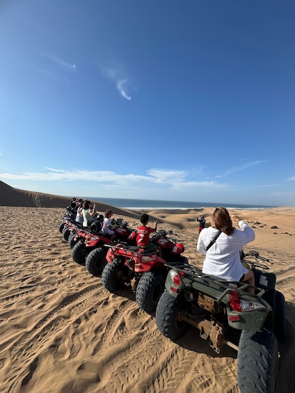 A group of people on ATVs in a desert with sand dunes and a clear sky. 1
