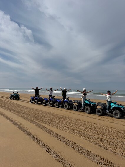 A group of people on ATVs on a sandy beach with the ocean in the background. 4