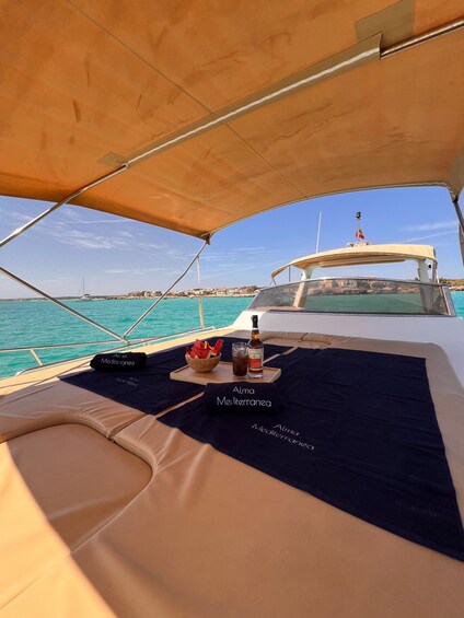 A boat deck with a table set for a meal, a bottle of alcohol, and a flag. 3