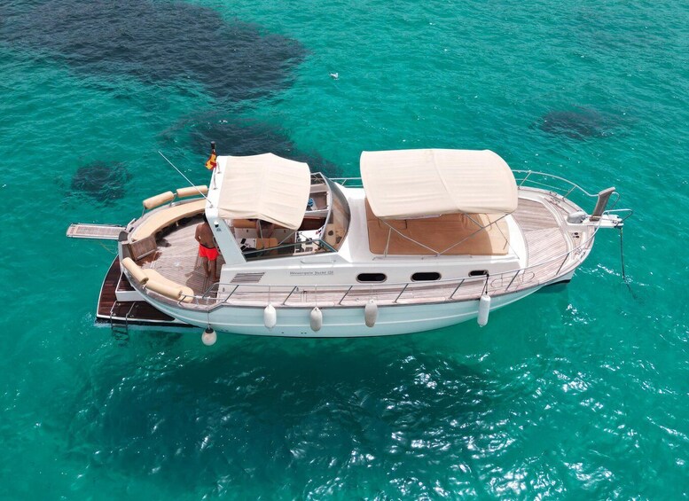 A small motorboat with two covered seating areas and a single person standing at the stern. 1