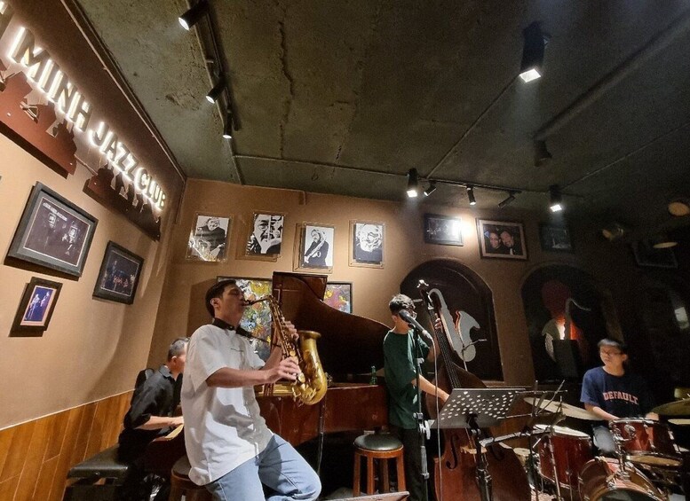 A jazz band performing in a dimly lit room with framed pictures on the walls. 2