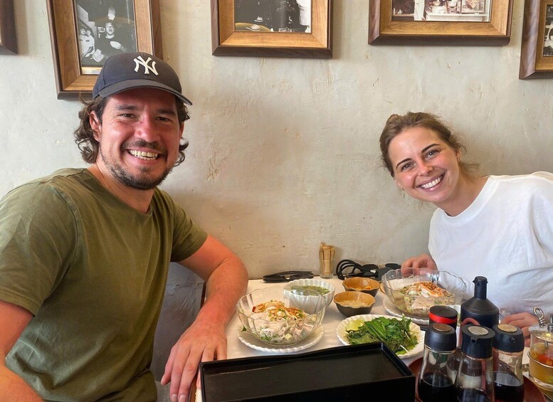 Two people seated at a table with various dishes and condiments. 4