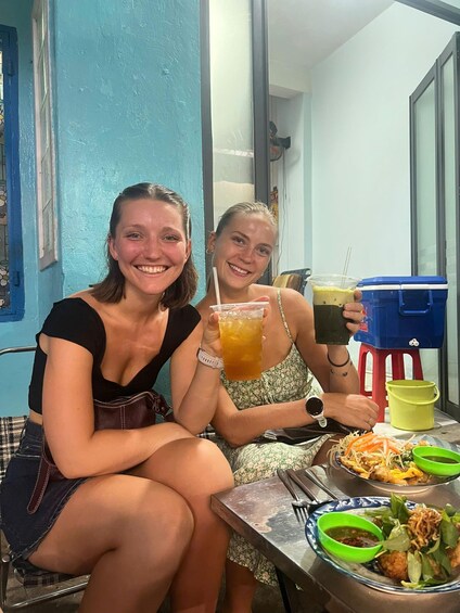 Two people sitting at a table with food and drinks. 5