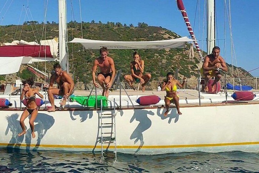 A group of people on a boat, some in swimwear, with a ladder and life buoys. 4