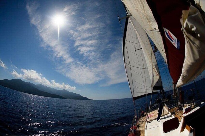A sailboat on the water with a clear sky and mountains in the background. 3