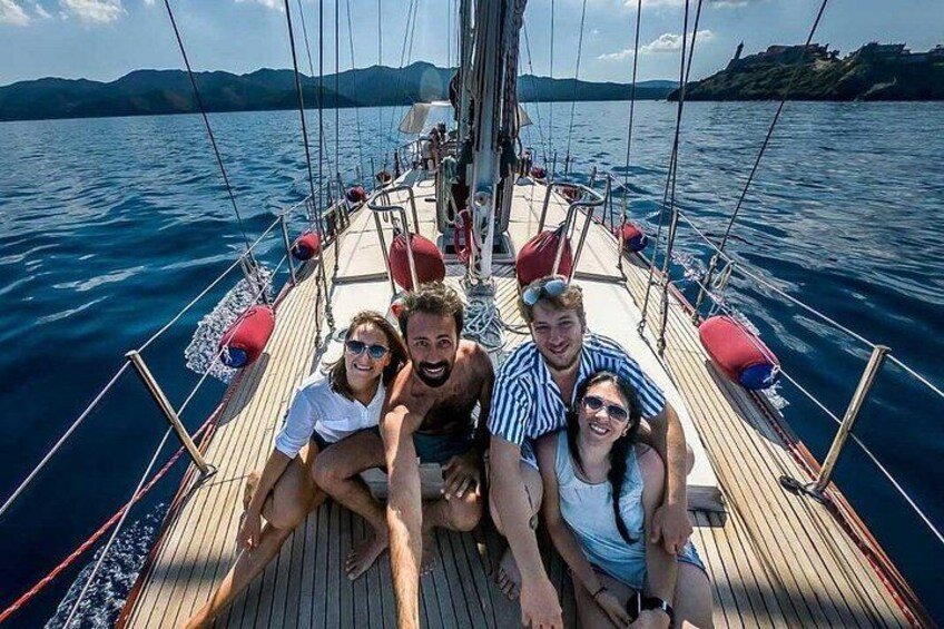 A sailboat with people on deck, a wooden deck, and a body of water with distant land. 5