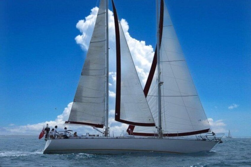 A sailboat with two sails on a calm sea under a clear sky. 2