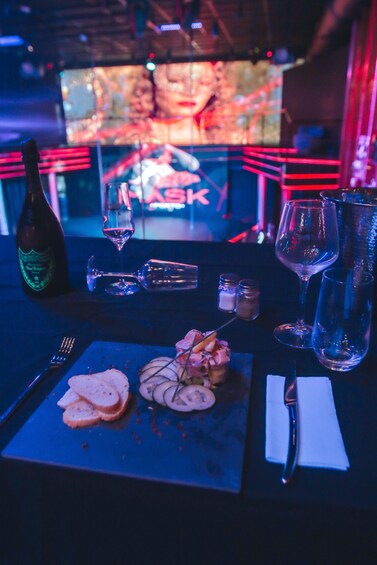 A bar setting with a bottle, glasses, and a plate of food. 3