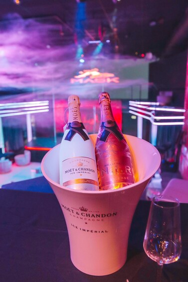 Two bottles of champagne in a bucket labeled 'MOET & CHANDON ICE IMPERIAL' with a glass beside it. 2
