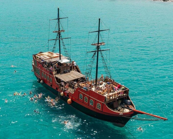 A red ship with two masts sailing on turquoise water. 1