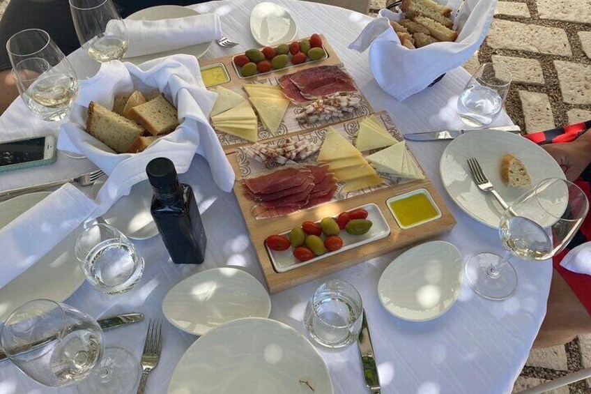 A picnic table with a charcuterie board, cheese, olives, and bread. 4