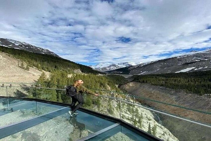 A person walking on a glass bridge with a mountainous landscape in the background. 2
