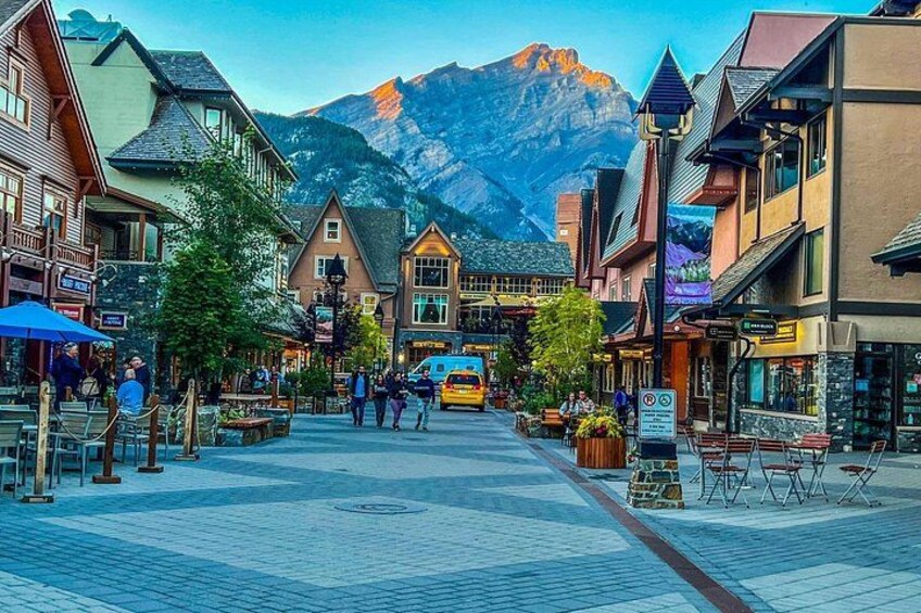 A town square with buildings, a mountain in the background, and a yellow bus. 2