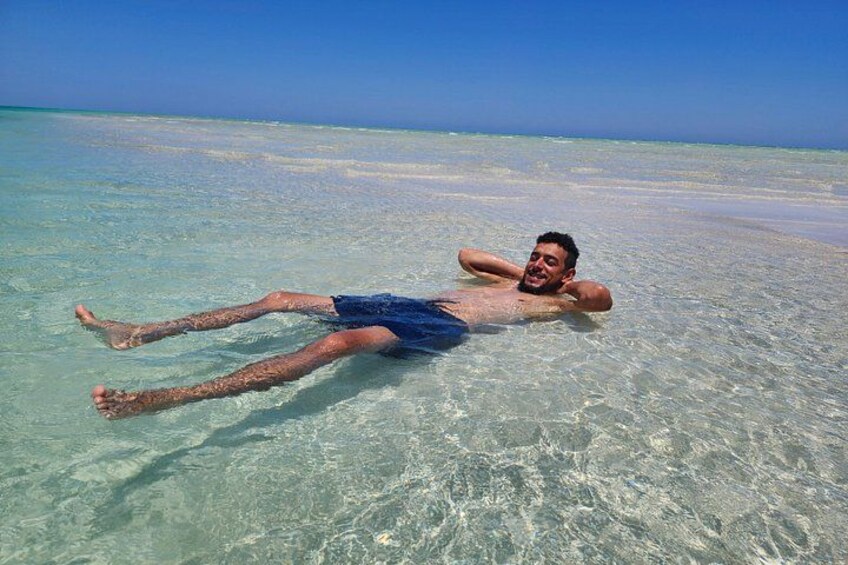 A person lying on a beach with clear water. 3