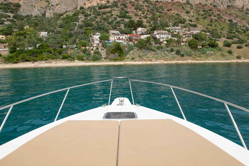 A boat's bow with a clear view of a coastal village and rocky hills in the background. 2