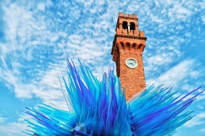 A tower with a clock, surrounded by blue and purple brush-like structures. 5