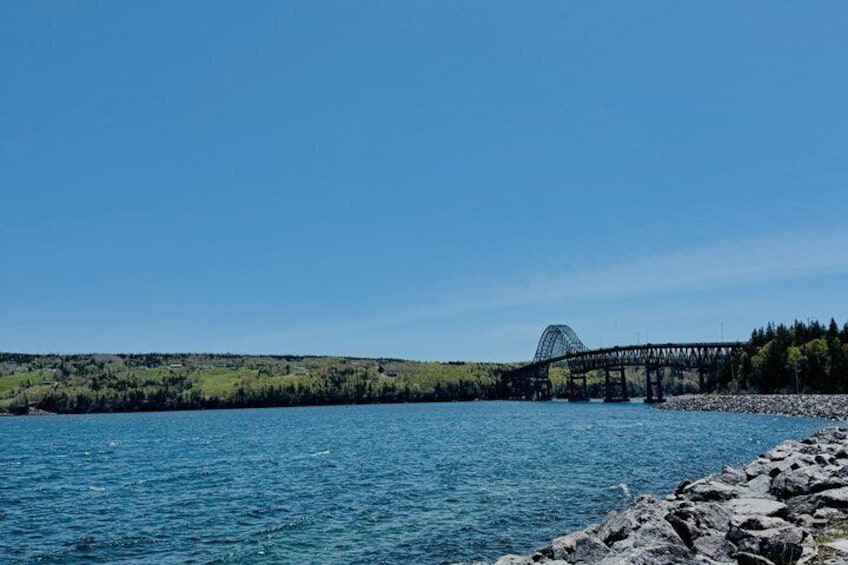 A bridge over a body of water with a forested hill in the background. 3