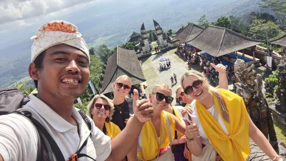 A group of people on a mountain trail with traditional architecture in the background. 1