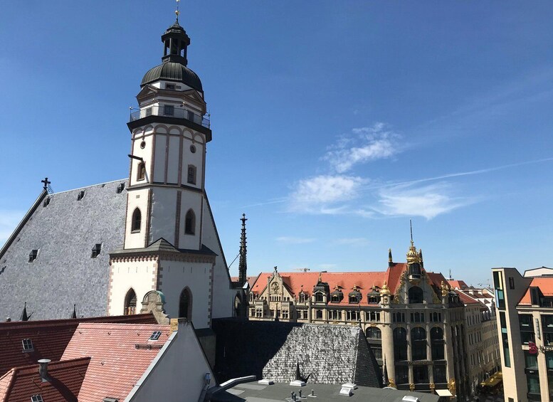 A church with a prominent tower and a red-roofed building with ornate details. 1
