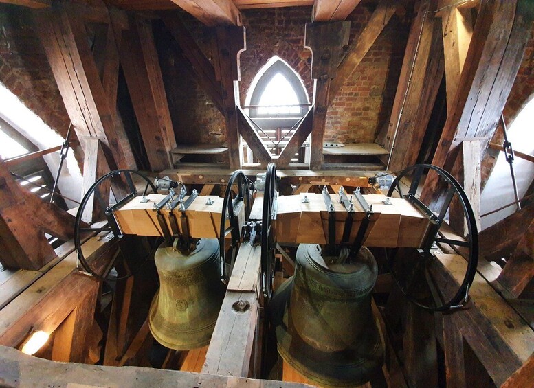 A bell tower with wooden beams, a central arched window, and two large bells. 2