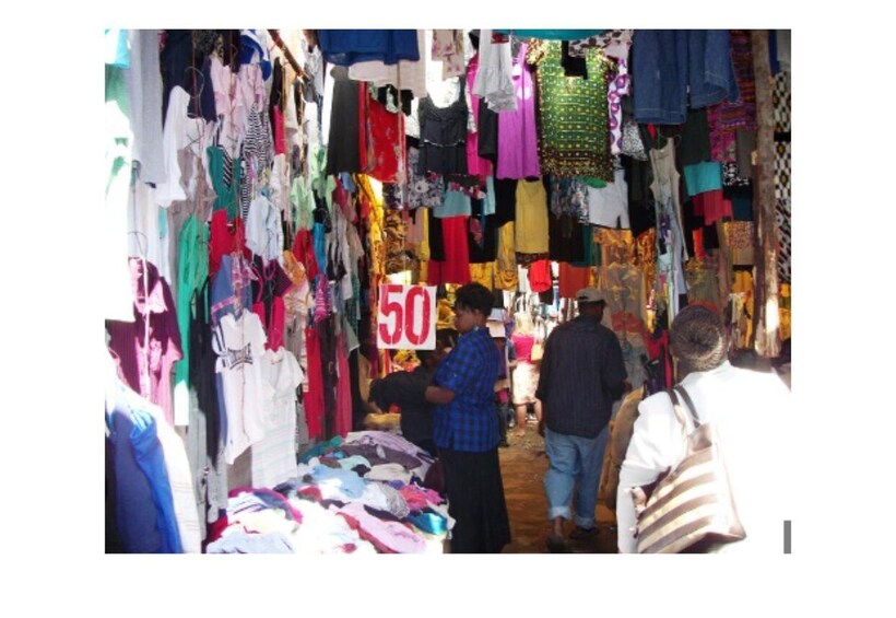 A market with various clothing items on display, a sign indicating a price of 50, and people browsing. 2