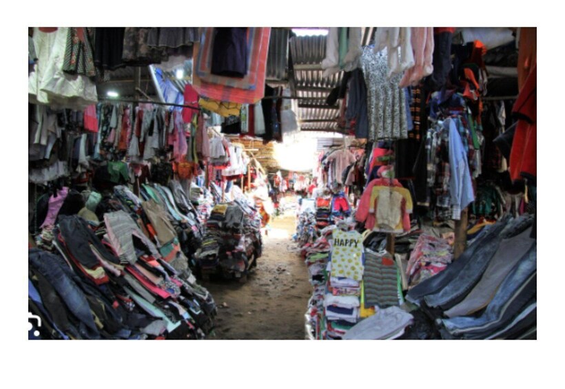 A crowded market with various clothing items on display. 3