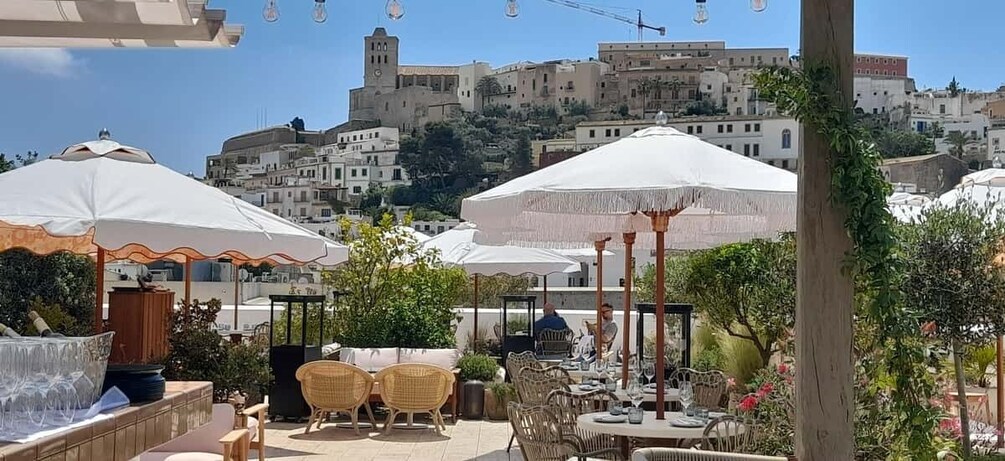 Outdoor seating with umbrellas, wicker chairs, and a view of a historic hilltop town. 4