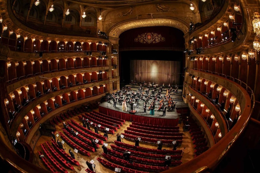 A grand theater with a circular stage, ornate decorations, and tiered seating. 1