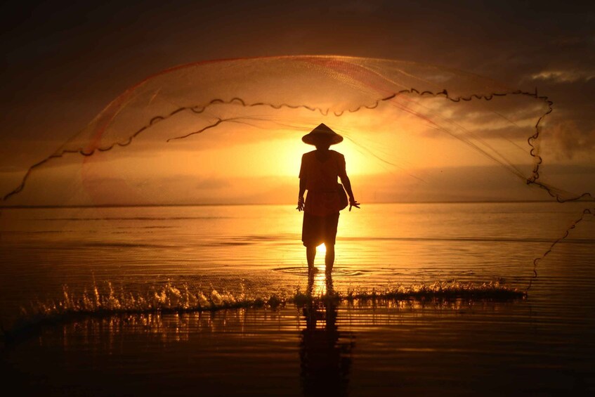 A silhouette of a person standing on a beach at sunset. 4