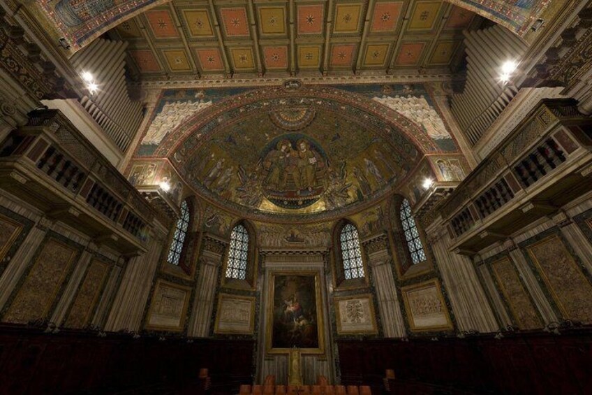 An ornate interior with a large circular mosaic, arched windows, and a central statue. 5