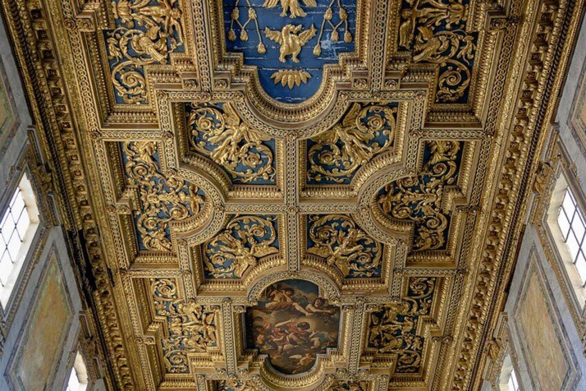 An ornate ceiling with intricate gold and blue designs, including a central medallion and surrounding figures. 2