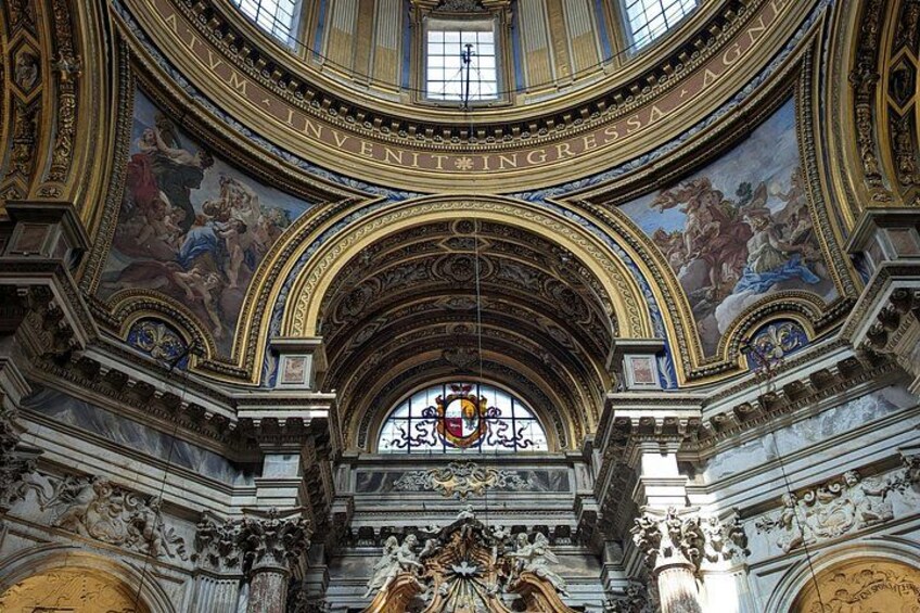 An ornate interior with a large circular stained glass window, intricate ceiling frescoes, and classical architectural elements. 4