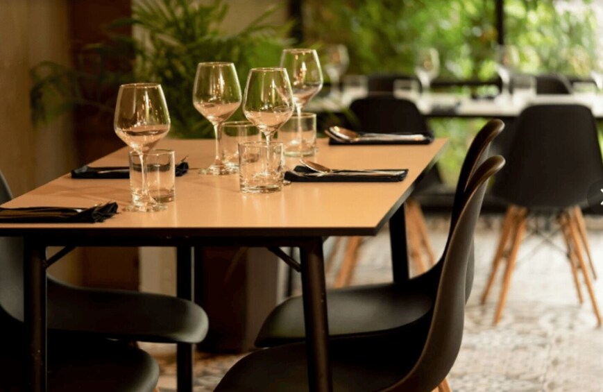 A restaurant table with wine glasses and cutlery, surrounded by chairs. 2