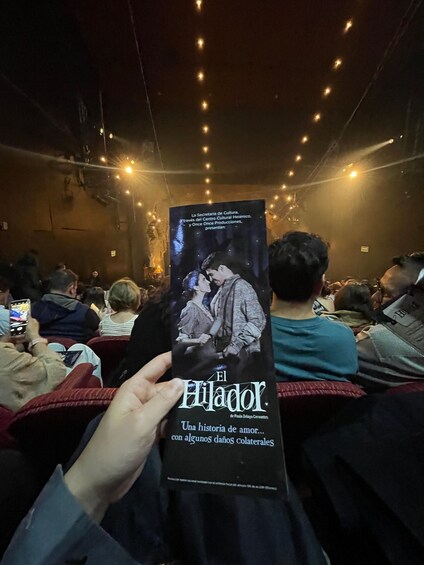 A person holding a movie poster in a dimly lit theater. 2