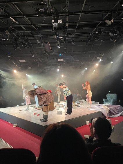 A stage with actors performing, a spotlight, and an audience. 3
