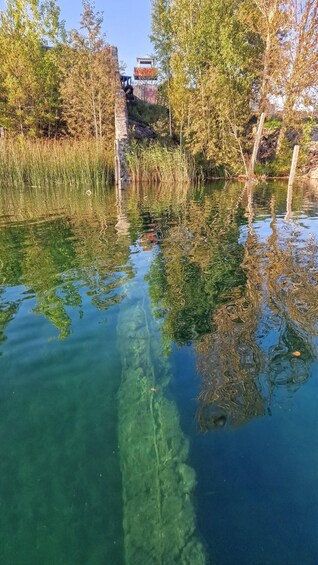 A clear pond with reflections of trees and a distant building. 4